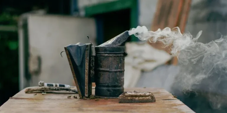 Close-up of a bee smoker releasing smoke on a wooden surface, outdoors