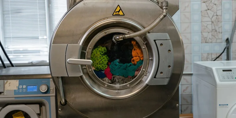 A close-up of an industrial washing machine operating in a laundry facility
