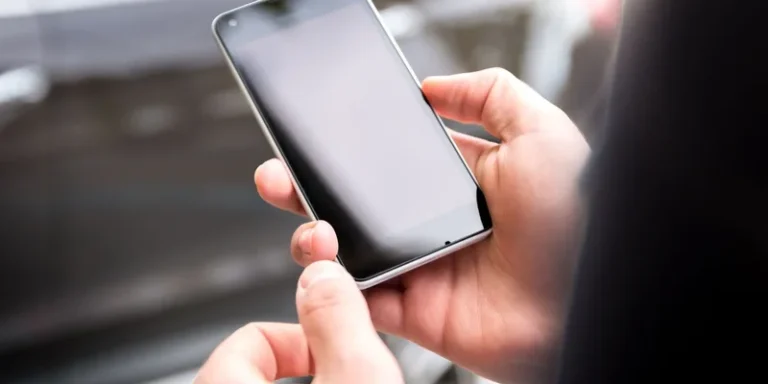 Close-up of hands holding a smartphone outdoors during the day