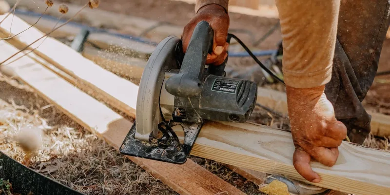 Carpenter operating a circular saw on wooden planks outside